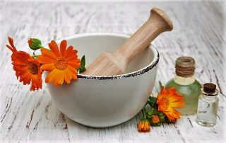 calendula flowers in mortar and massage oil on a wooden background